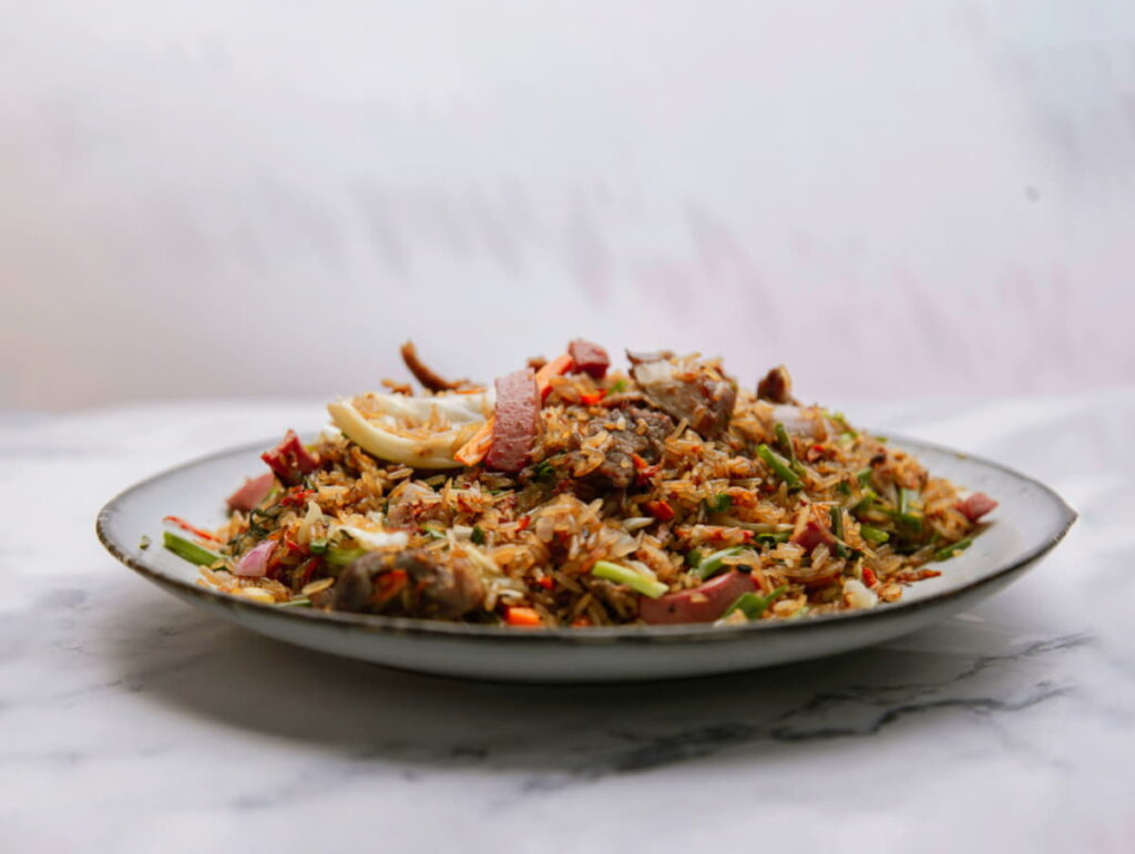 A plate of fried rice with vegetables on a white dish