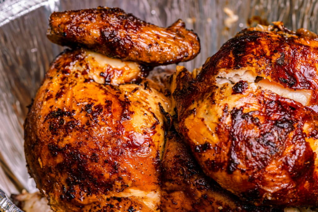 Close-up detail of roasted rotisserie chicken skin showing charred, crispy texture.