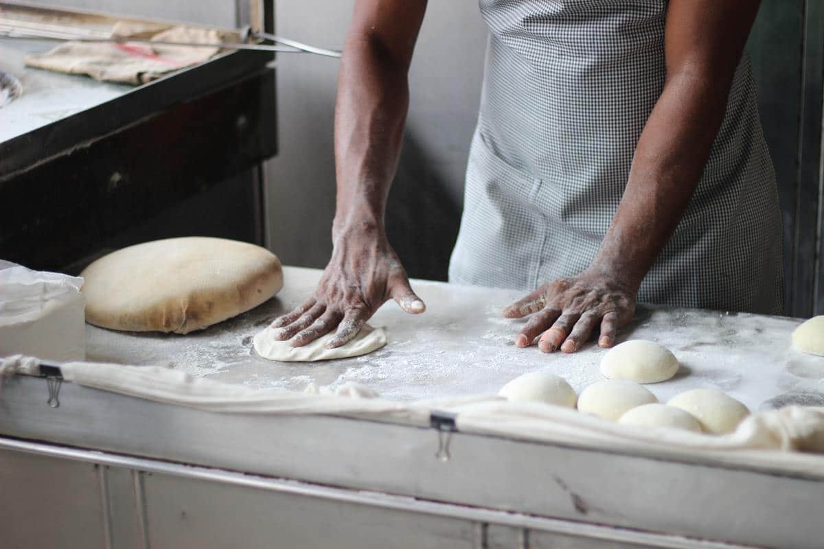 Man Rolling Out Pizza Dough on a Dusted Table