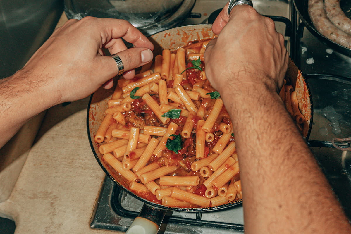 man warming up pasta on the stovetop