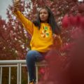 Woman in a Yellow Sweatshirt Sitting on a Fence Looking Good 'AF'