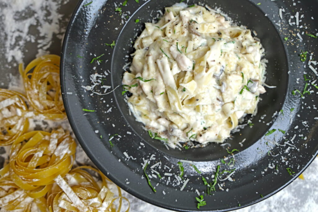 Overhead shot of creamy Alfredo sauce in a pan, showing smooth texture and white parmesan flecks.