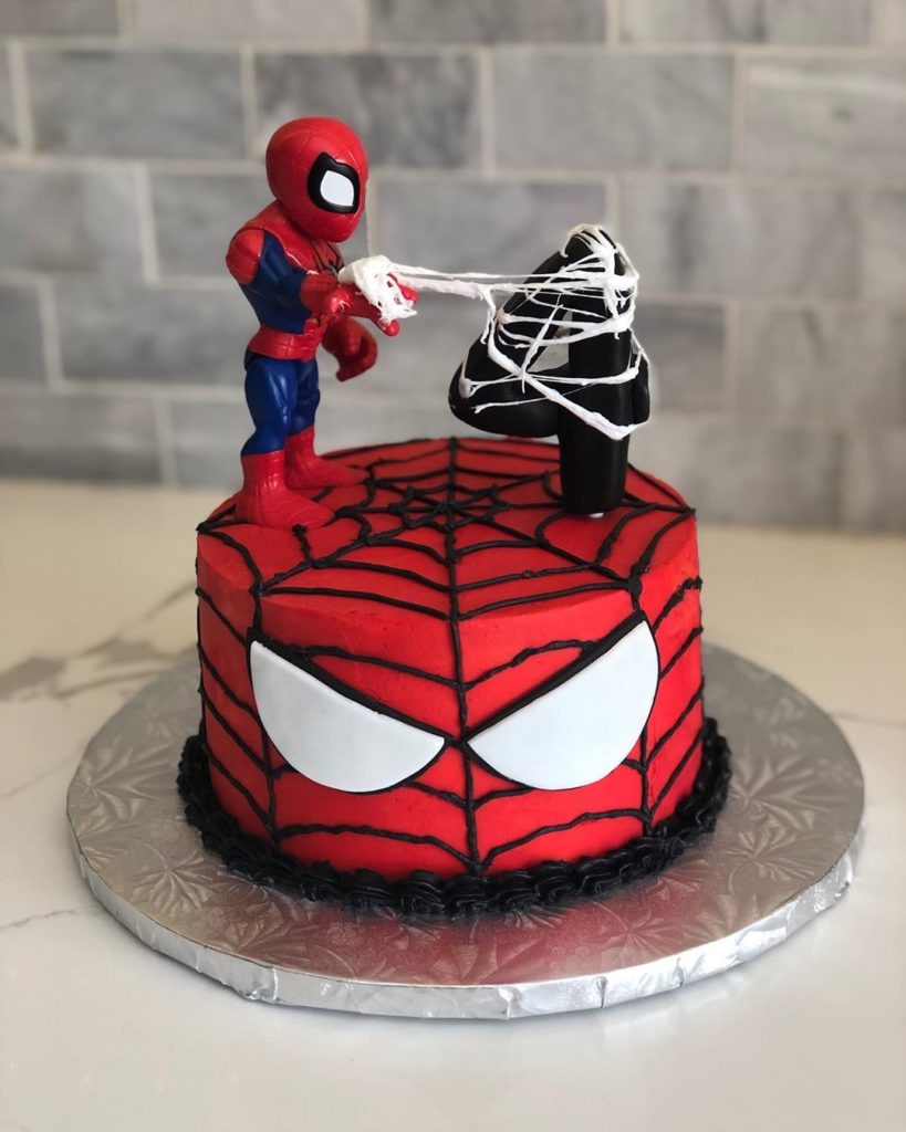 Spiderman cake with a small Spiderman standing on his face