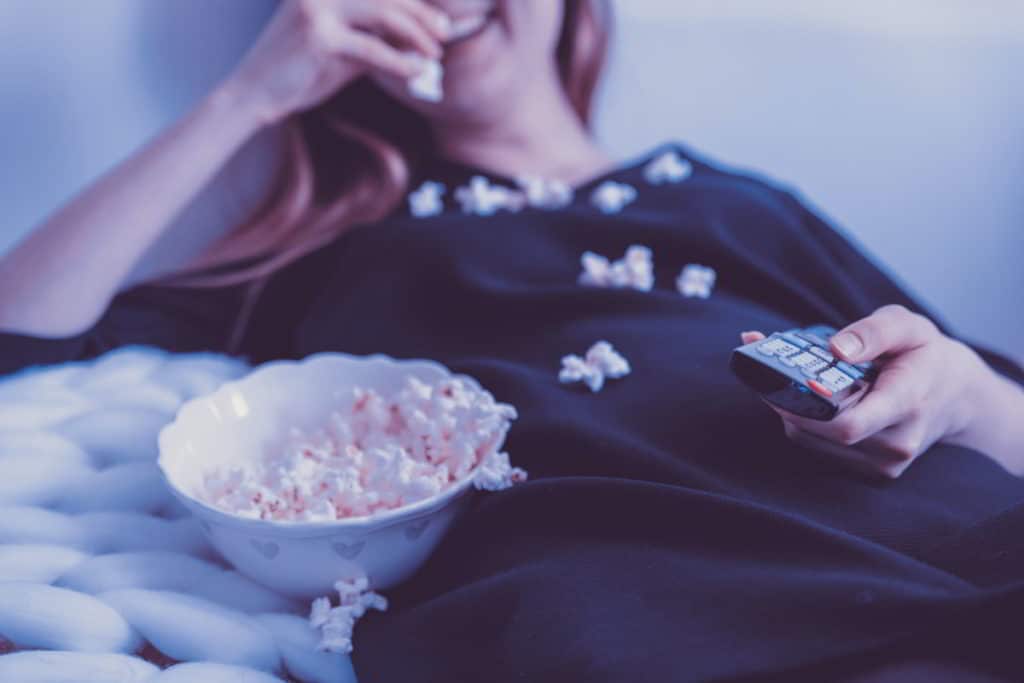 A Woman Eating a Bowl of Popcorn in Bed