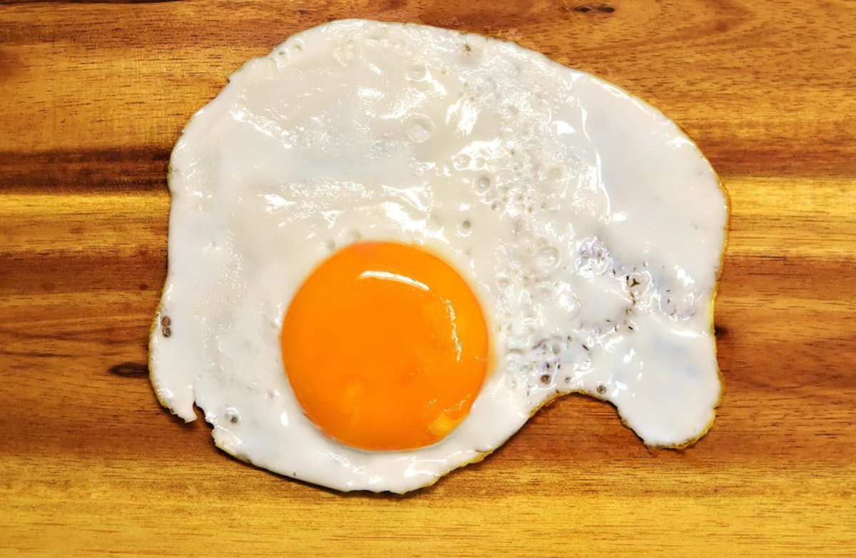 overhead shot of a fried egg on a cutting board