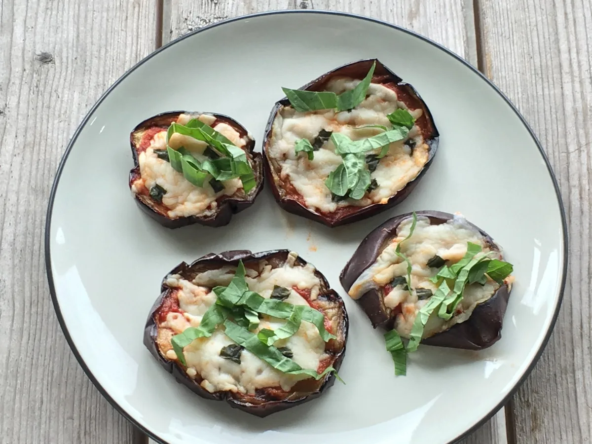 Roasted eggplant rounds topped with tomato sauce, melted mozzarella and herbs