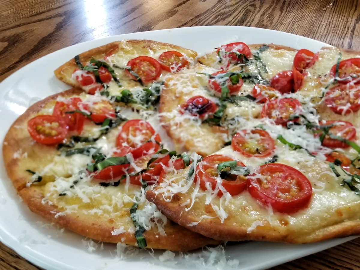 Naan flatbread pizza topped with mozzarella, cherry tomatoes and fresh basil