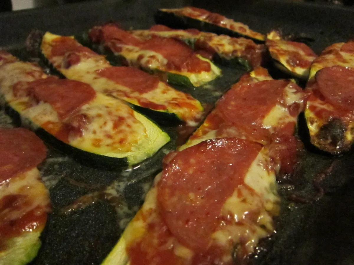 Baked zucchini rounds topped with tomato sauce, melted cheese and herbs